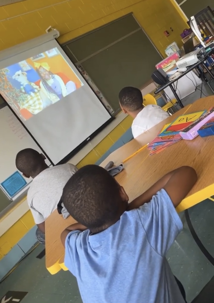 Two toddlers clap along to a calming animation on a classroom screen